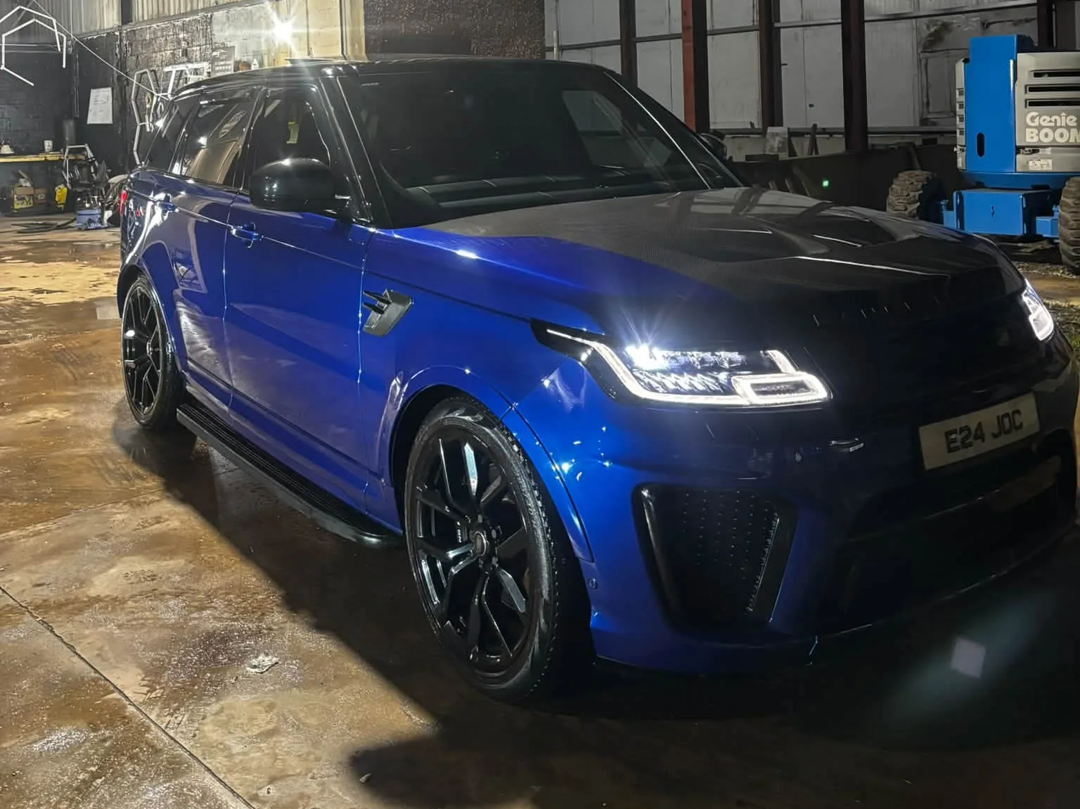 Blue Range Rover SVR with its lights on, outside the unit at night after its winter package